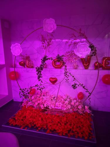 a room with pink lights and roses and flowers at LovRoom deco Re & Spacieux in Ris-Orangis