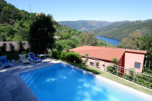 a swimming pool with a view of a house and a lake at Casa da Loja in Vieira do Minho