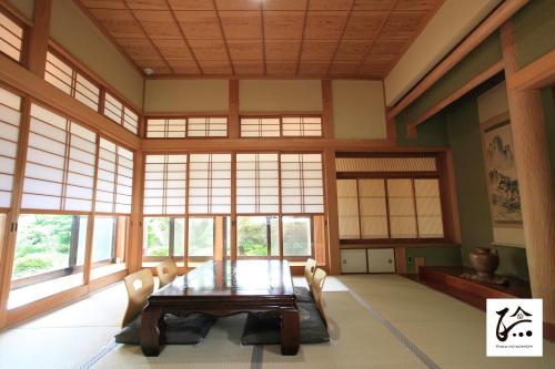 a dining room with a table and chairs and windows at 旅庭 福の小径 Ryotei Fukunokomichi in Isahaya