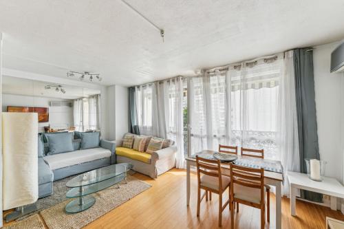 un salon avec un canapé, une table et des chaises dans l'établissement Chic and comfortable apart with balcony, à Levallois-Perret