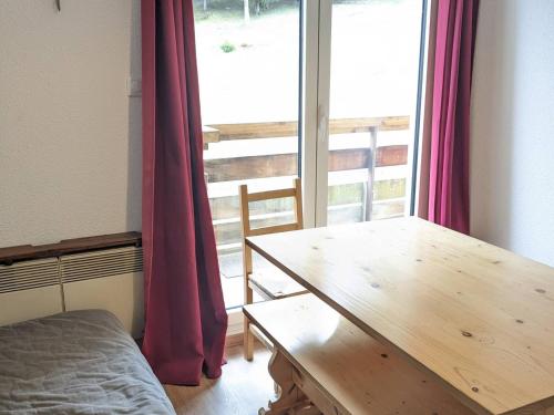 Cette chambre dispose d'une table en bois et d'une grande fenêtre. dans l'établissement 2 pièces au pied des pistes avec balcon et équipements complets - FR-1-557-95, à Les Adrets