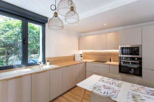 une cuisine avec des armoires blanches, un évier et une fenêtre dans l'établissement Superbe maison proche de Paris!, à Sceaux