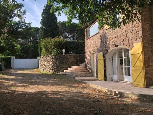 une maison en briques avec une porte jaune et des escaliers dans l'établissement La Ventourinado Villa 12 personnes Piscine chauffée, à Sainte-Maxime