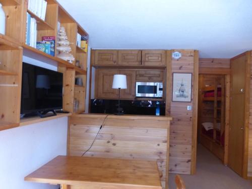 - une cuisine avec des placards en bois et une table dans une pièce dans l'établissement Studio confortable à Méribel Altiport, skis aux pieds, terrasse ensoleillée, proche forêt - FR-1-411-835, à Les Allues
