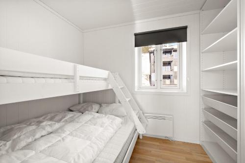 a white bedroom with a bunk bed and a window at Voss Resort self-service apartments in Skulestadmo