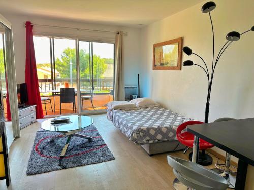 - une chambre avec un lit, une table et un balcon dans l'établissement Grand Studio Avec Piscine Presqu'île De Giens, à Hyères