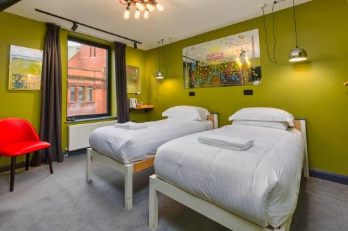 two beds in a room with green walls and a red chair at ART B&B in Blackpool