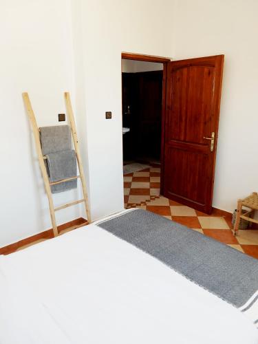 a bedroom with a bed and a wooden door at Olas Surf Camp in Imsouane