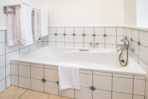 a white bathroom with a tub and white tiles at Luxury Lodge at Pinnacle Point in Mossel Bay