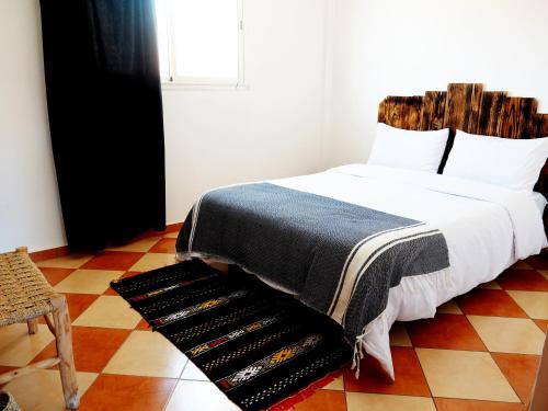 a bedroom with a bed with a blanket on it at Olas Surf Camp in Imsouane