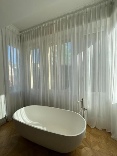 a white bath tub in a bathroom with curtains at Delle Nazioni Milan Hotel in Milan