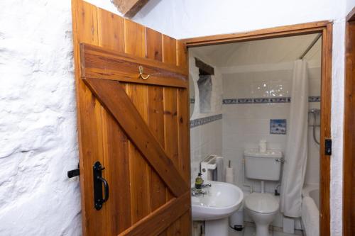 a bathroom with a wooden door and a toilet at Ivy Cottage in Pyle