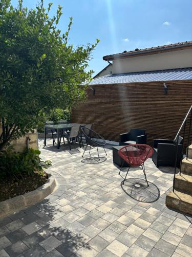 d'une terrasse avec des chaises, une table et un mur en briques. dans l'établissement La maison des vignes, à Saint-Dizier