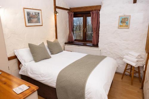 a bedroom with a white bed and a window at Ivy Cottage in Pyle