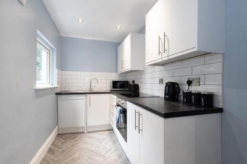 a kitchen with white cabinets and a black counter top at Modern Boutique Studios in Central Bolton Perfect for Contractors & Short Stays in Bolton
