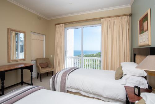 a hotel room with two beds and a desk and a window at Lifestyle Villa at Pinnacle in Mossel Bay