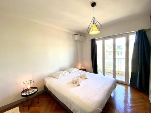 ein großes weißes Bett in einem Zimmer mit einem großen Fenster in der Unterkunft Large flat terrace Sea view, Promenade des Anglais in Nizza