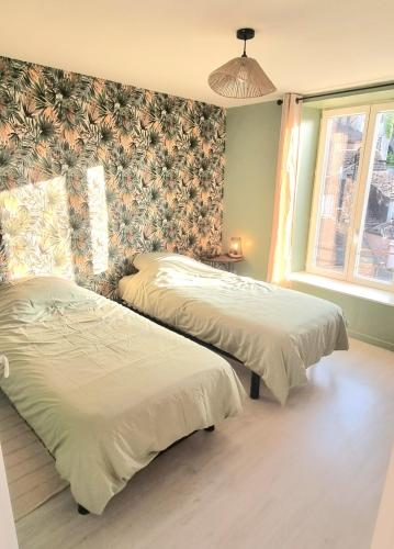 deux lits dans une chambre avec papier peint fleuri dans l'établissement New appartement nature cœur de ville, à Avesnes-sur-Helpe