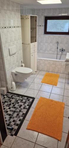 ein Badezimmer mit einer Badewanne, einem WC und 2 Teppichen in der Unterkunft Stadtrand Wilhelmshaven in Schortens