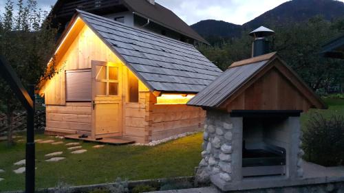 a small cabin with a stone fireplace in the yard at Apartments Klemenčič in Bohinj