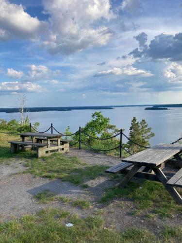 two picnic tables in front of a body of water at Nyrenoverad liten stuga i Marmorbruket in Kolmården