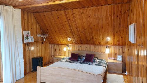 Cottage Zawoja في زافويا: غرفة نوم مع سرير في غرفة بألواح خشبية