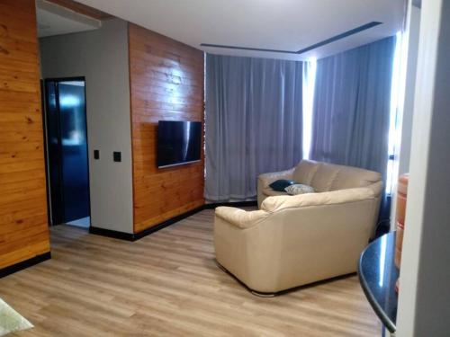 a living room with a white couch and a television at Apartamento aconchegante de montanha in São Roque