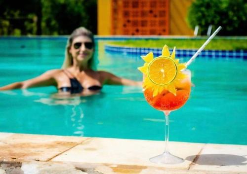 a woman in a swimming pool with a margarita drink at Angá Beach Hotel in São Miguel dos Milagres