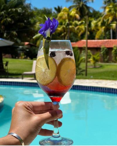 a person holding a drink with a flower in it at Angá Beach Hotel in São Miguel dos Milagres
