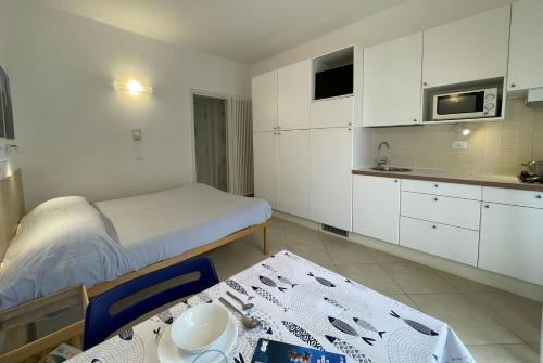 a room with a bed and a table and a kitchen at Residence Glicini in Finale Ligure