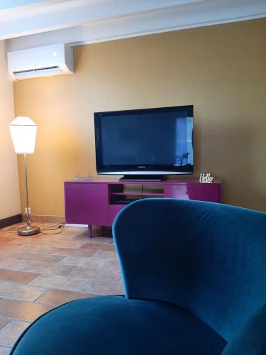 a living room with a tv and a blue chair at Gite climatisé L'Orée des Landes Proche Center Parcs in Pindères