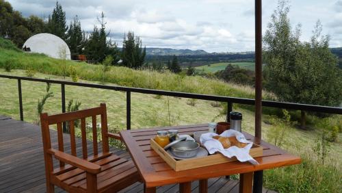 a tray of food on a wooden table on a deck at Santuario Glamping in Subachoque