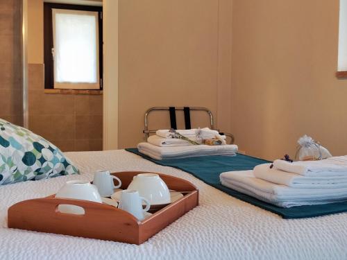a tray with cups and towels on a bed at La Fonte Delle Faranghe by Host Hero in Esanatoglia