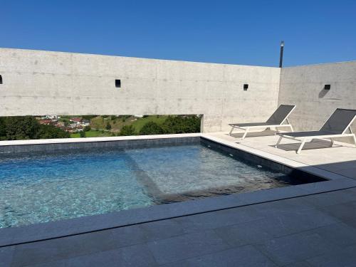 a swimming pool with two chairs next to a building at Vila Trnovac in Bužim