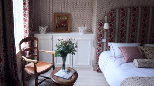 a bedroom with a bed and a table with a vase of flowers at Maison Mouche in Beaumont-en-Auge