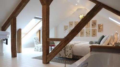 a attic bedroom with a bed and a bath tub at Maison Mouche in Beaumont-en-Auge