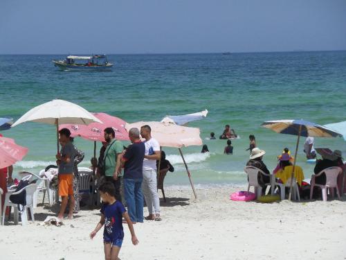 a group of people standing on a beach with umbrellas at برج بيلو بيتش in Alexandria