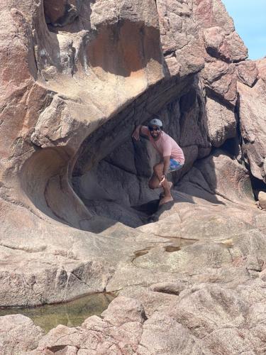a man is sitting in a rock cave at Olas Surf Camp in Imsouane