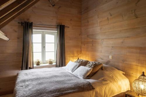 a bedroom with wooden walls and a bed with a window at Vakantiehoeve Amadee in Zonnebeke