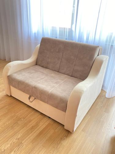 a couch sitting in a living room next to a window at Light house in Sombor