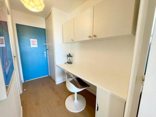 Cette chambre comprend un bureau blanc et une porte bleue. dans l'établissement STUDIO VUE MER Quartier des Quilles, à Sète