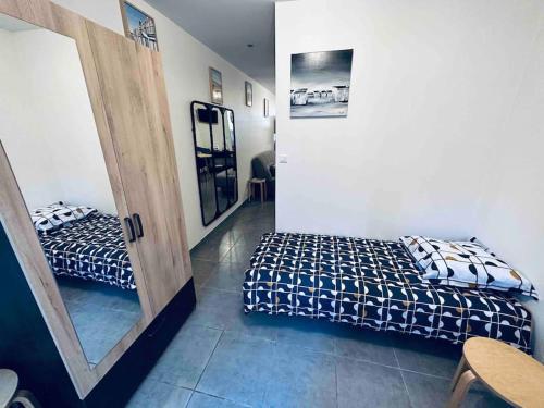 Cette chambre comprend 2 lits et un miroir. dans l'établissement Studio 3 personnes centre ville, avec cour, à Calais