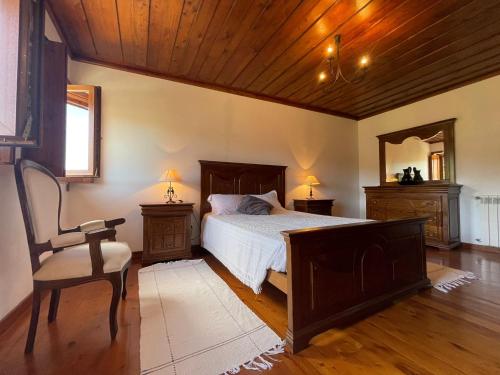 a bedroom with a bed and a chair and a mirror at Casa d'Avó Lina - Gerês in Terras de Bouro