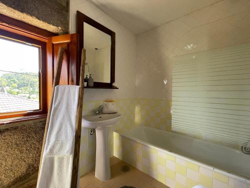 a bathroom with a tub and a sink and a mirror at Casa d'Avó Lina - Gerês in Terras de Bouro