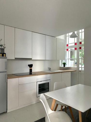 une cuisine avec des armoires blanches et une table et des chaises dans l'établissement Le temps d'un passage, appartement de charme en plein centre historique, à Montpellier