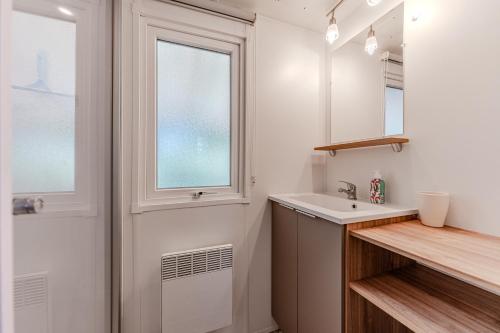 a white bathroom with a sink and a window at Mobile home Gastes in Gastes