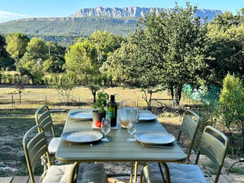a picnic table with chairs and a bottle of wine at Maisonette Sainte Victoire in Fuveau