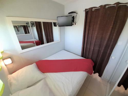 une petite chambre avec un lit et un miroir dans l'établissement Appartement Village Naturiste Tentation, au Cap d'Agde
