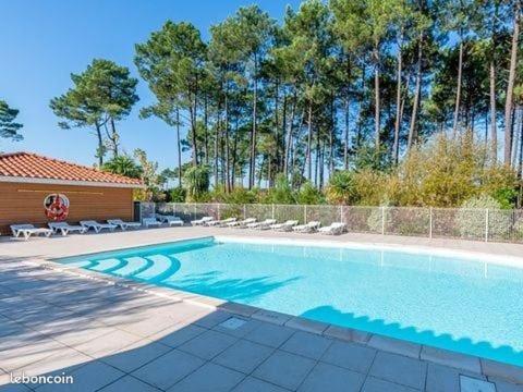 une piscine avec des chaises et une clôture dans l'établissement Chalet dans résidence de vacances, 3 chambres, piscines, jacuzzi, au bord du lac, à Parentis-en-Born