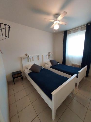 une chambre avec deux lits et un ventilateur de plafond dans l'établissement Chalet dans résidence de vacances, 3 chambres, piscines, jacuzzi, au bord du lac, à Parentis-en-Born